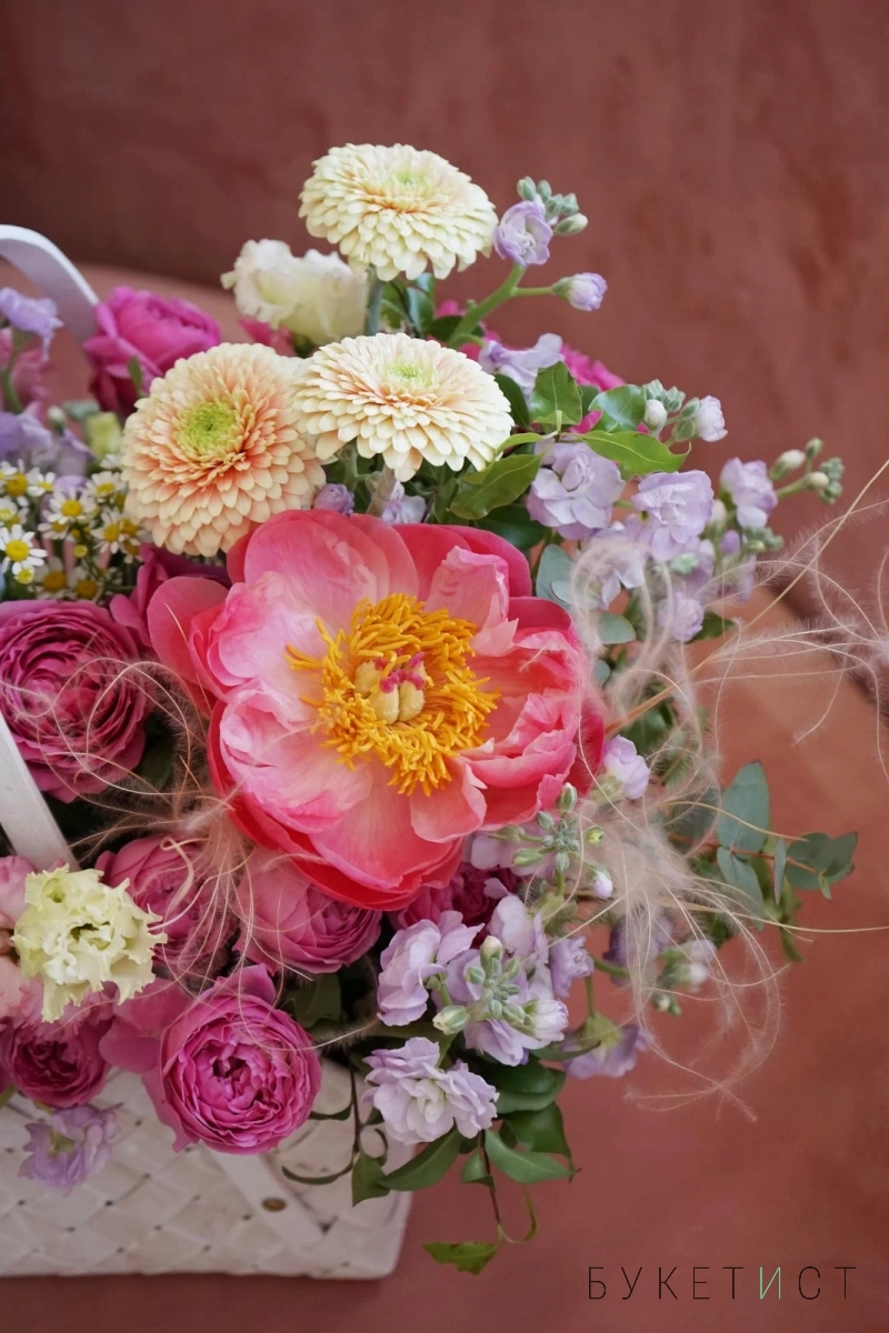 Сезонный букет цветов пионов и роз в плетёной сумке