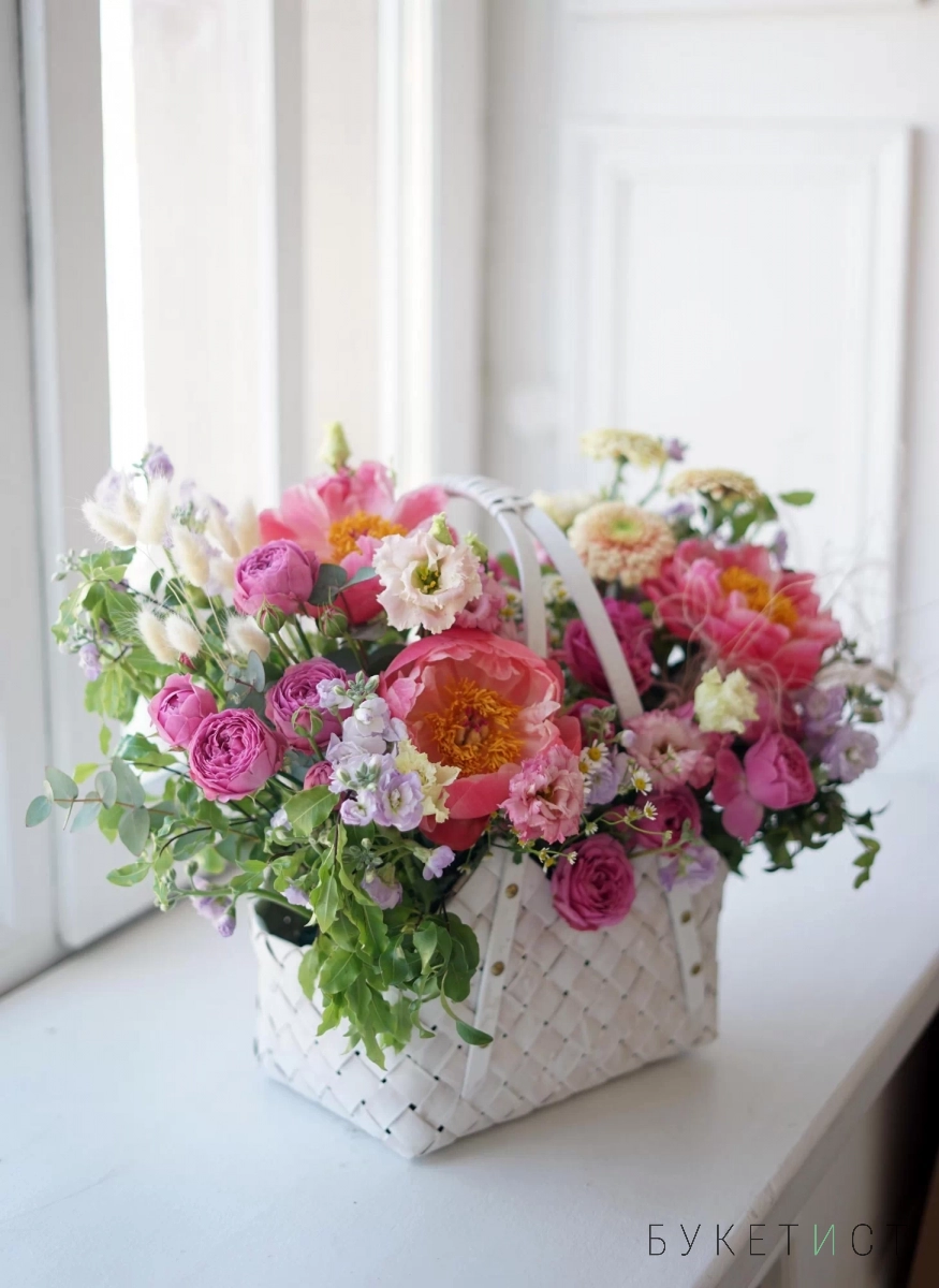 Сезонный букет цветов пионов и роз в плетёной сумке