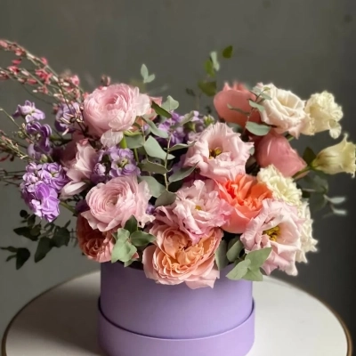 Композиция лавандового оттенка с ранункулюсами и пионовидными розами в шляпной коробке