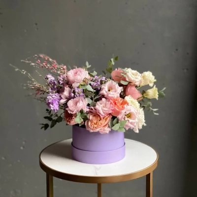 Композиция лавандового оттенка с ранункулюсами и пионовидными розами в шляпной коробке